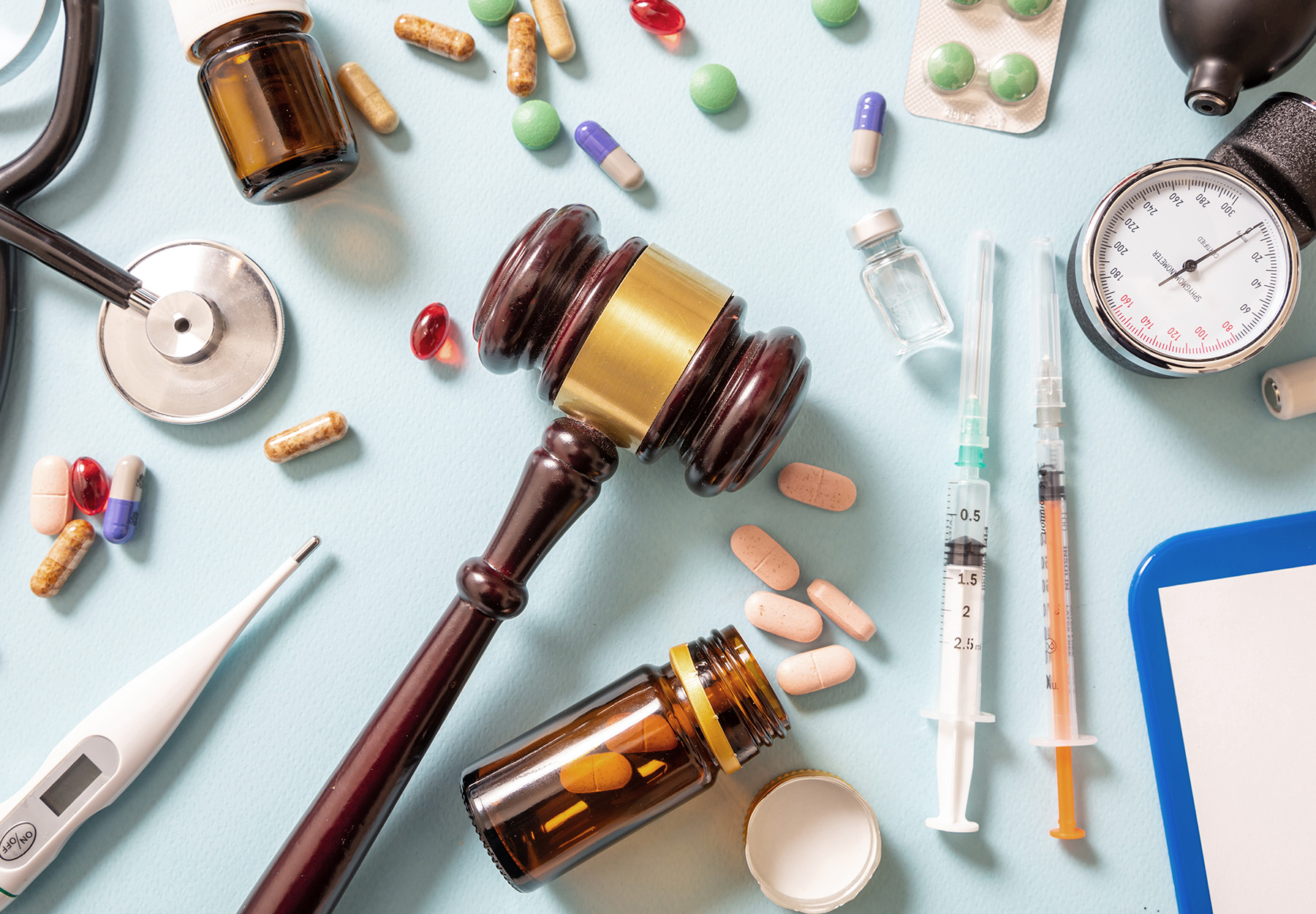 Health and Law flat lay. Judge gavel, medicine and doctor coat on blue, background, top view. Healthcare fraud concept. iStock image