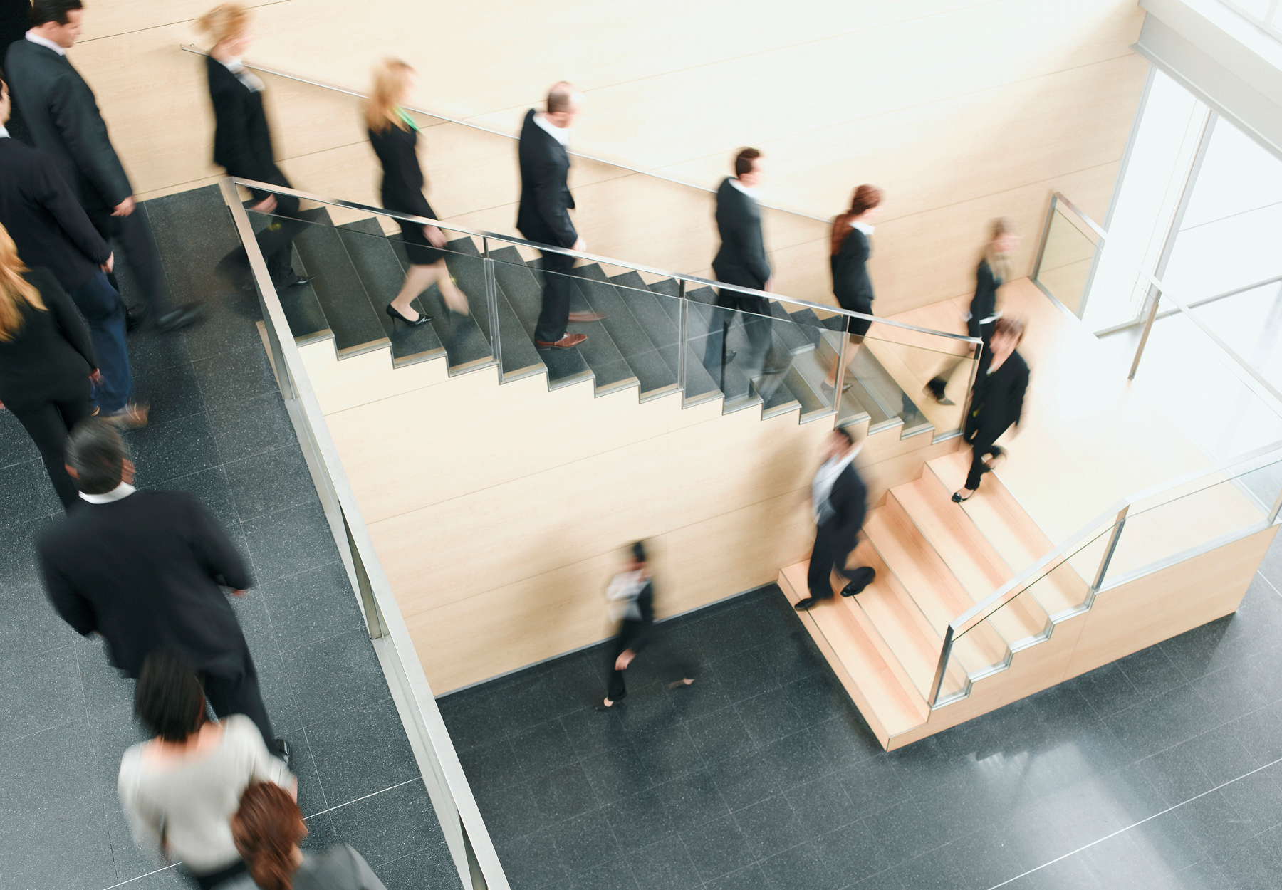 People in business attire walk down the stairs of an office building. Layoffs concept. iStock image.