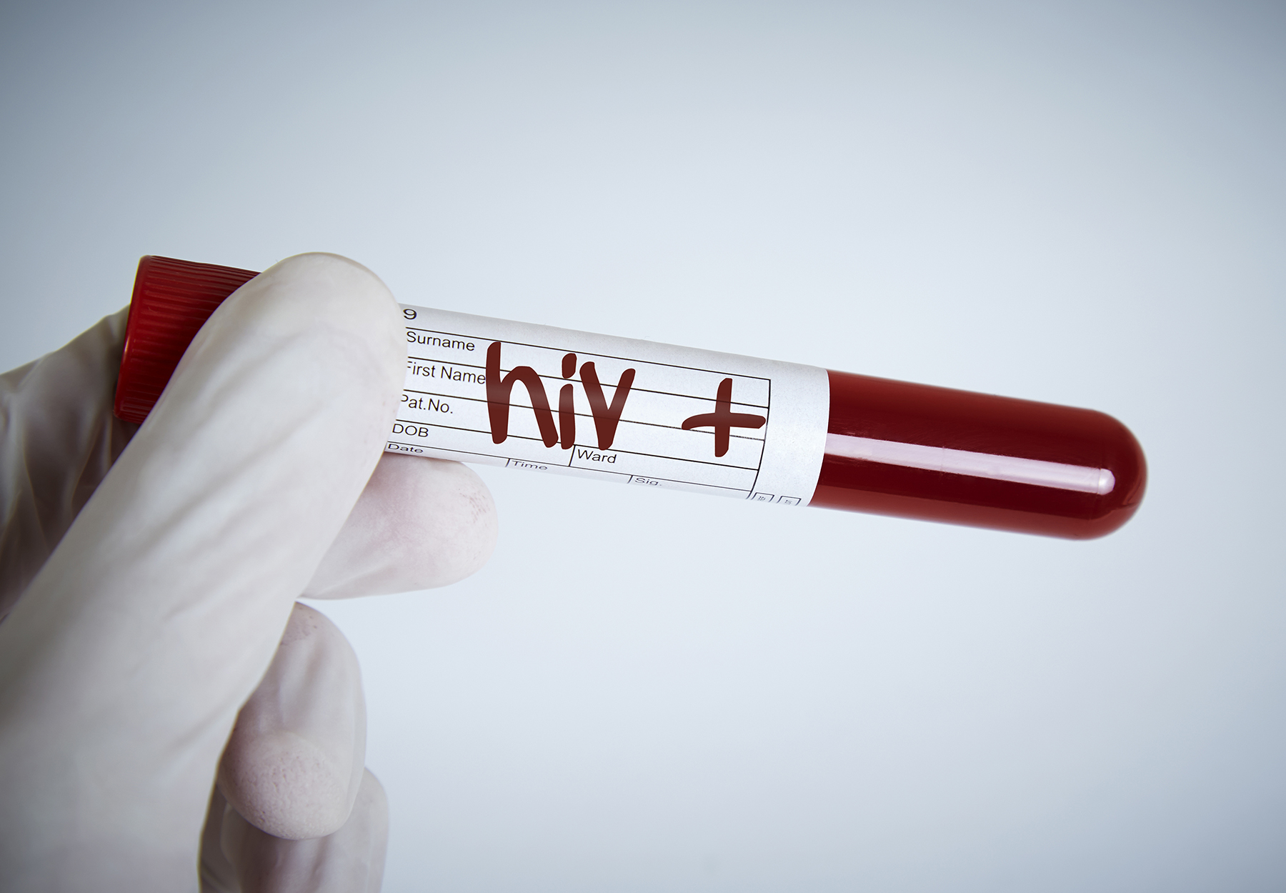 Gloved hand holding test tube of blood with 