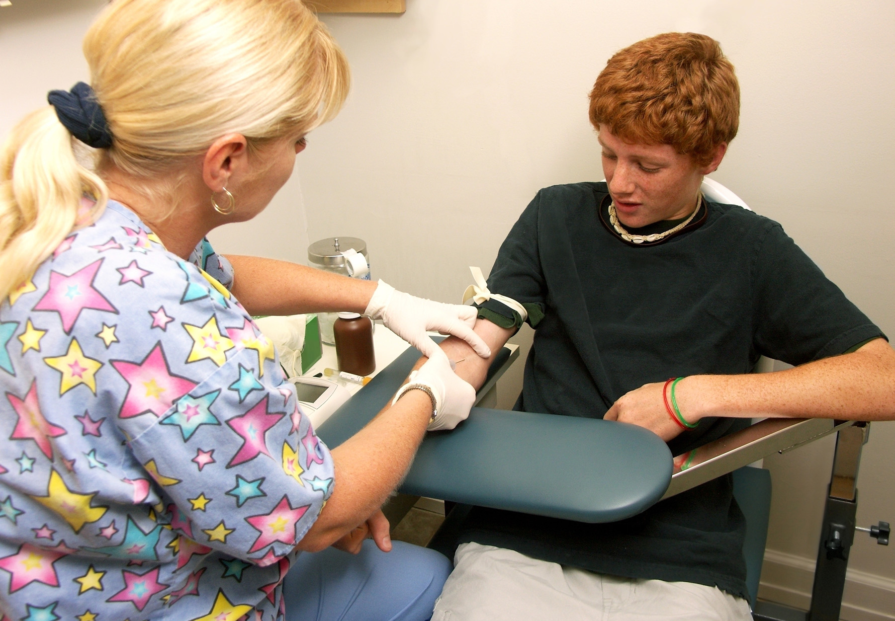 Red-haired male teen gets a blood draw from a female nurse. iStock image.