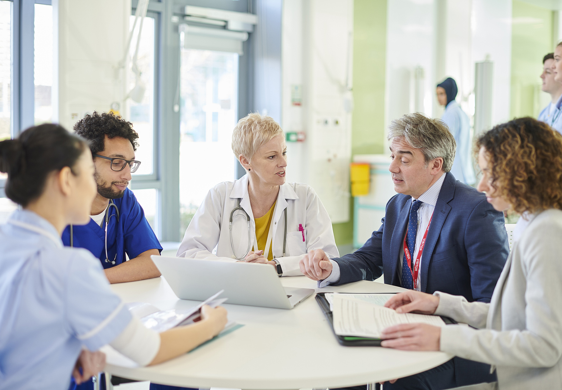 A group of healthcare professionals meet with a laboratory sales rep at a round table in the facility.