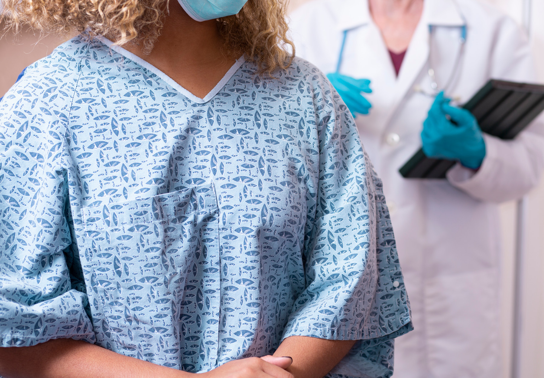 Closeup of female patient, who is getting ready for breast cancer screening, with a doctor in the background. iStock image.