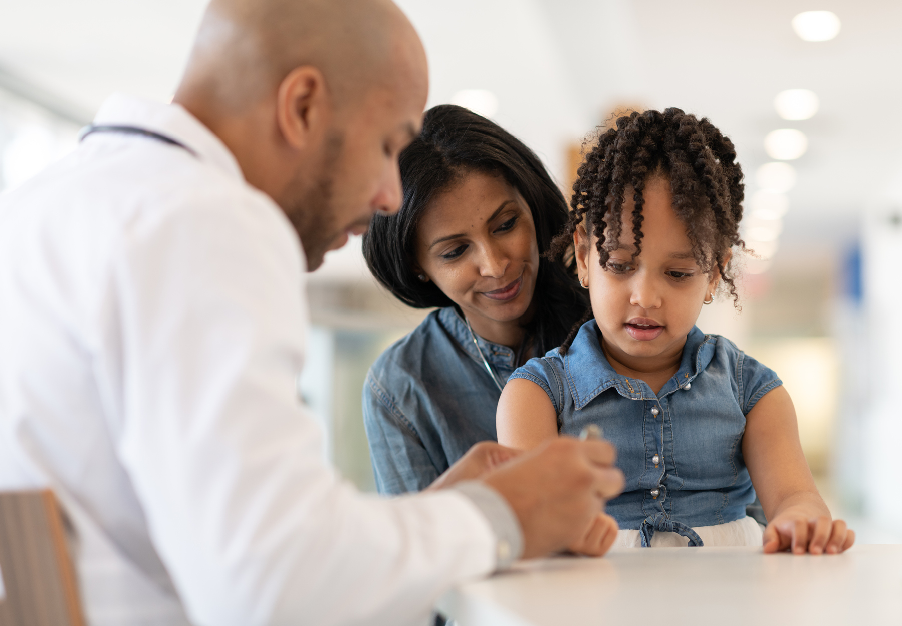 Mother with young daughter meet with male doctor.