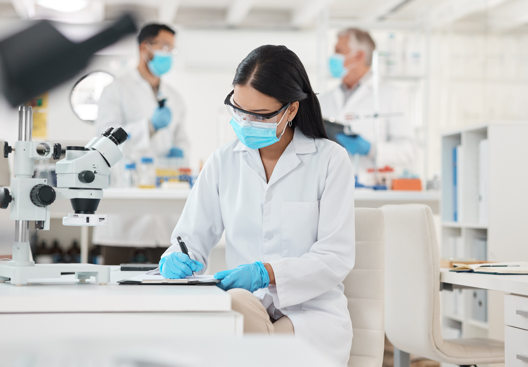 Shot of a young female scientist writing notes while working in a lab stock photo.