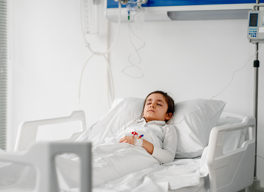 Little girl resting in hospital bed with IV drip.