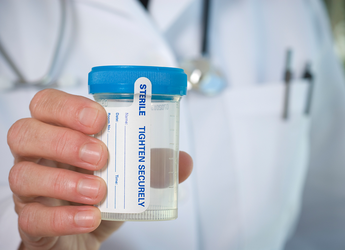 Doctor's hand holding out empty urine sample container. Urine drug testing concept.