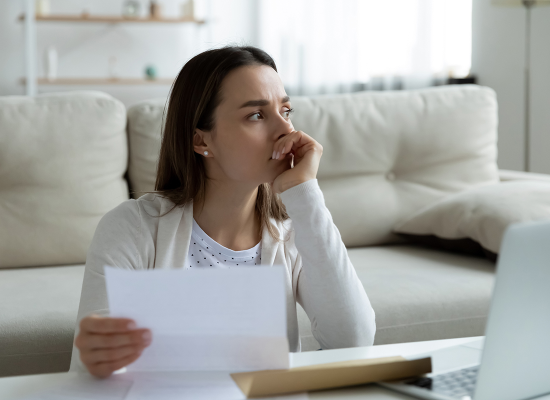 Thoughtful unhappy frustrated young woman holding medical bill. Debt concept.