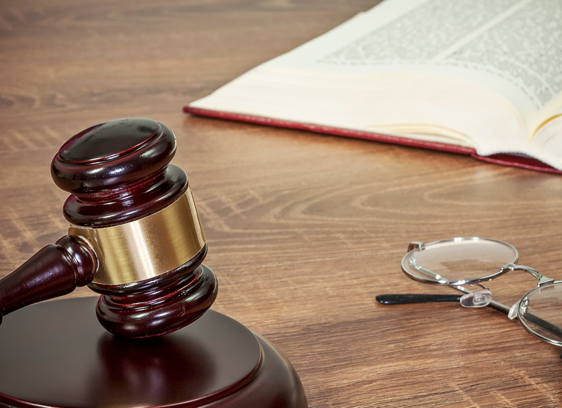 Judge's gavel on desk with eyeglasses and book. Legal concept.