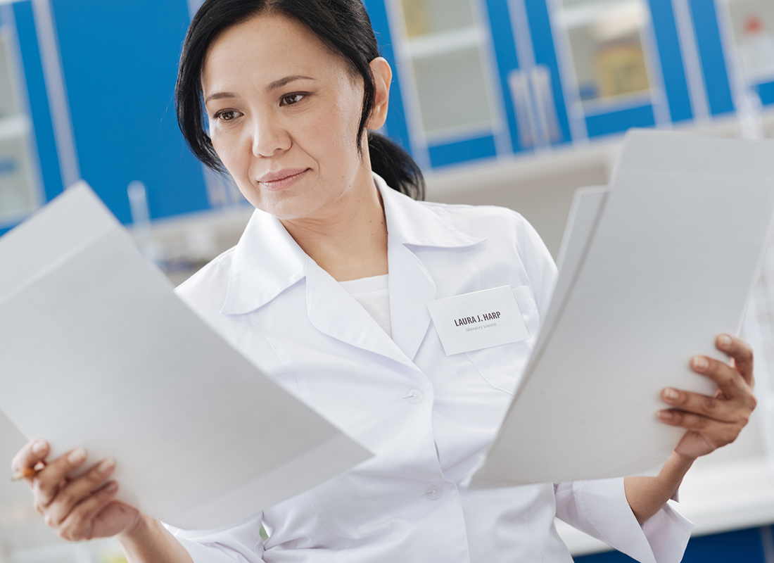 Female lab professional standing in the lab and reading documents.