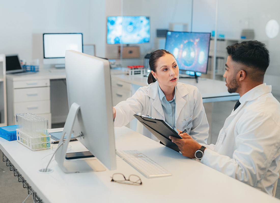 Lab professionals sitting at a desk and having a conversation.