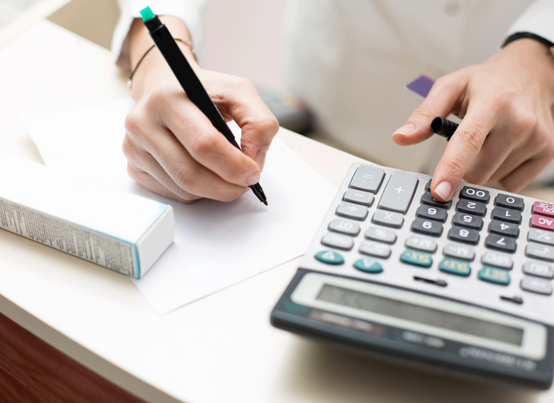 Closeup of laboratory leader budgeting at a desk with a pen, paper, and calculator.