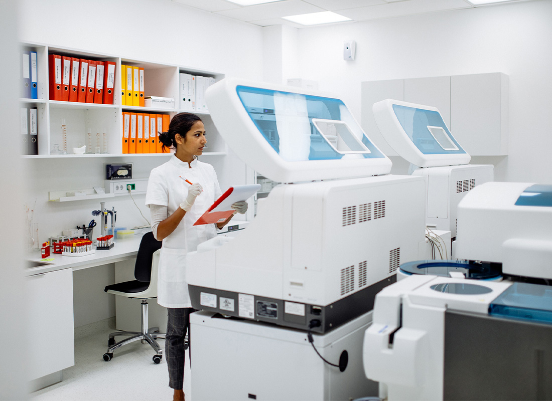 A female lab professional examines hematology instruments in the laboratory.