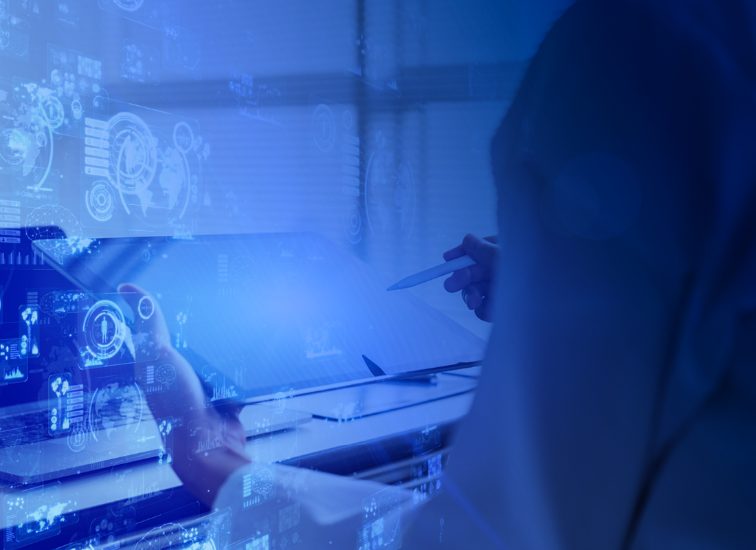 A laboratory professional uses a tablet while sitting in front of a computer with various health-related icons coming out of it to illustrate the concept of healthcare regulations