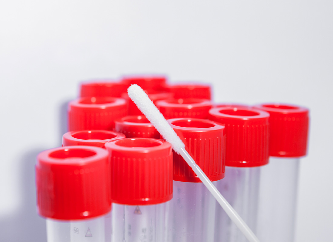 A set of test tubes with a swab leaning against them, illustrating the concept of genetic testing.
