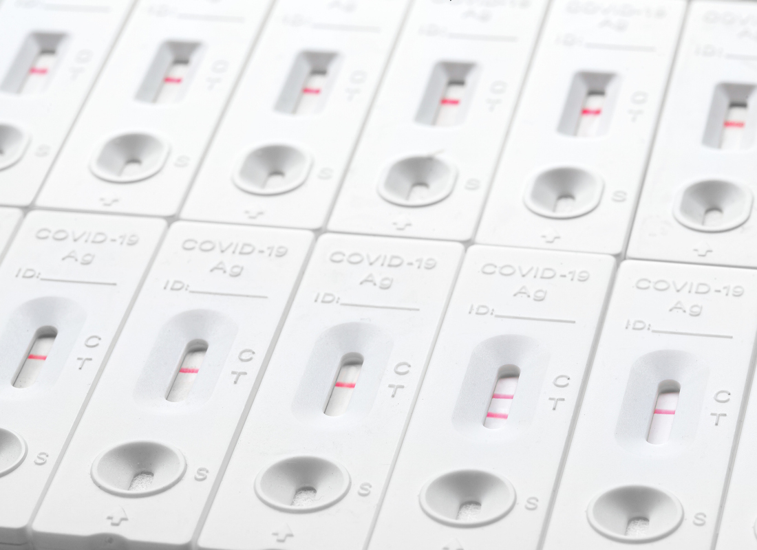 Rows of COVID-19 test cartridges on a white background, viewed from above.