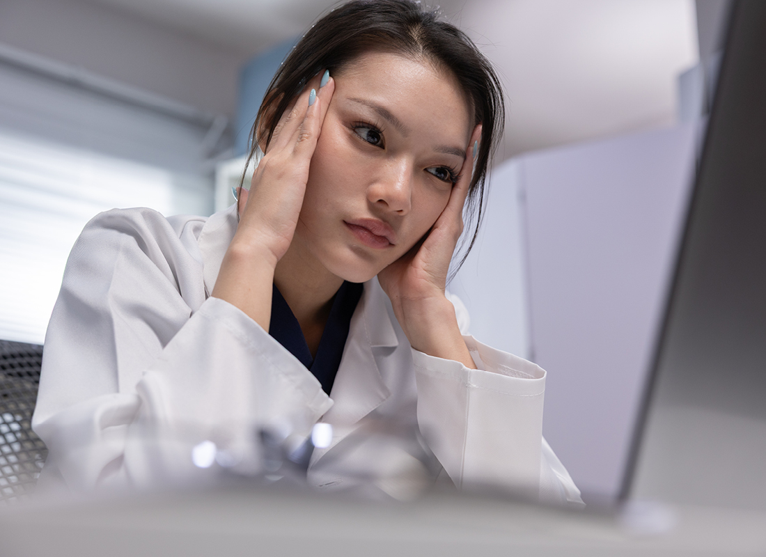 Woman in medical coat holds her temples